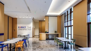 A modern conference room with a large table and chairs, a counter with stools, and a slogan on the wall. - Holiday Inn Express Haikou West Coast by IHG (Haikou)