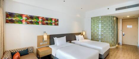 A hotel room with two beds, a sofa, a desk, and a large abstract painting on the wall.