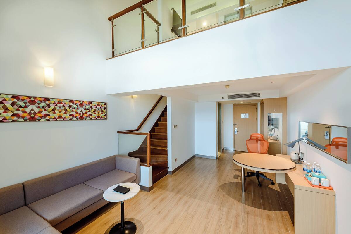 A modern interior with a staircase, a sofa, a dining table, and a kitchen area.