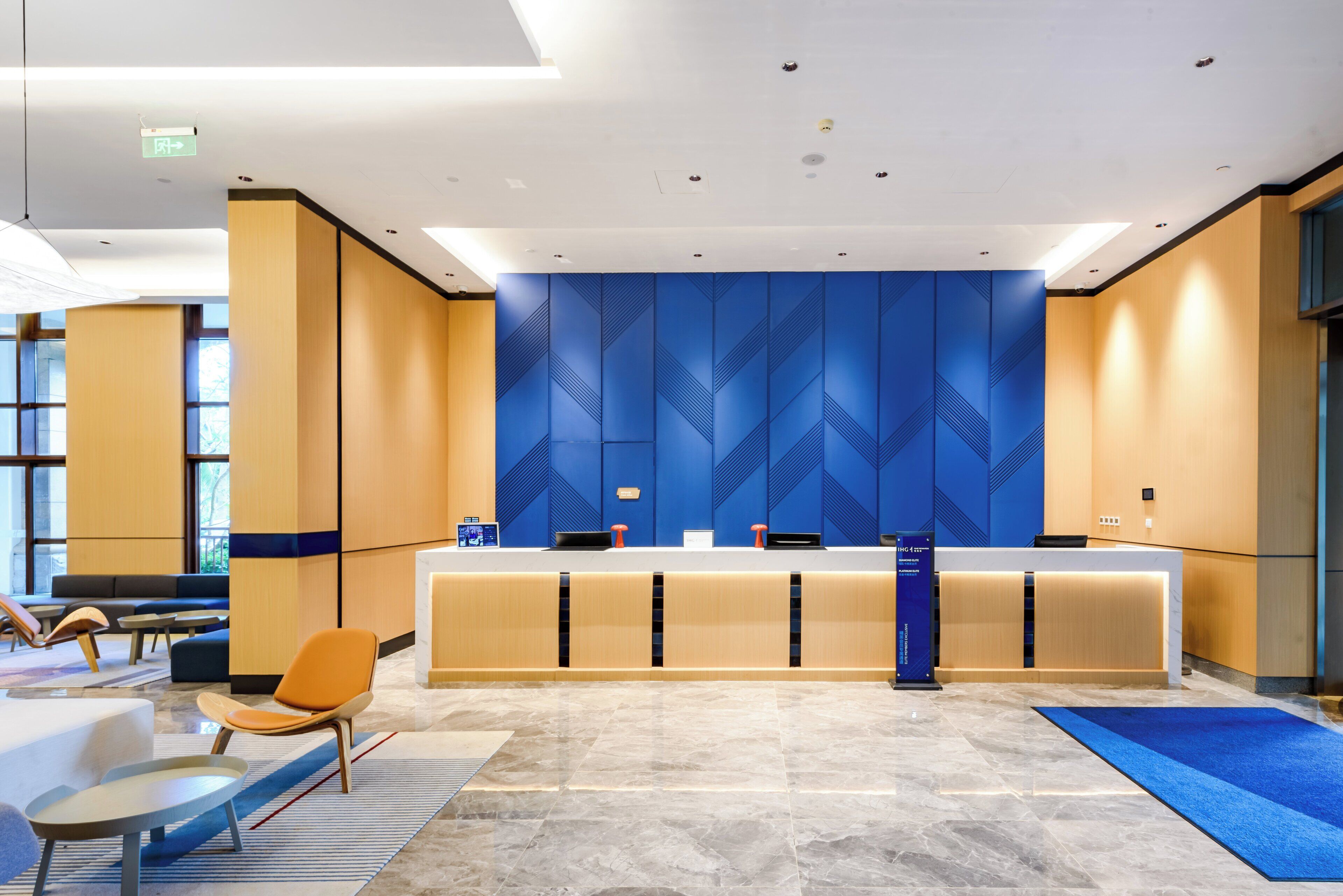 Un moderno vestíbulo de hotel con mostrador de recepción, zona de estar y amplios ventanales.