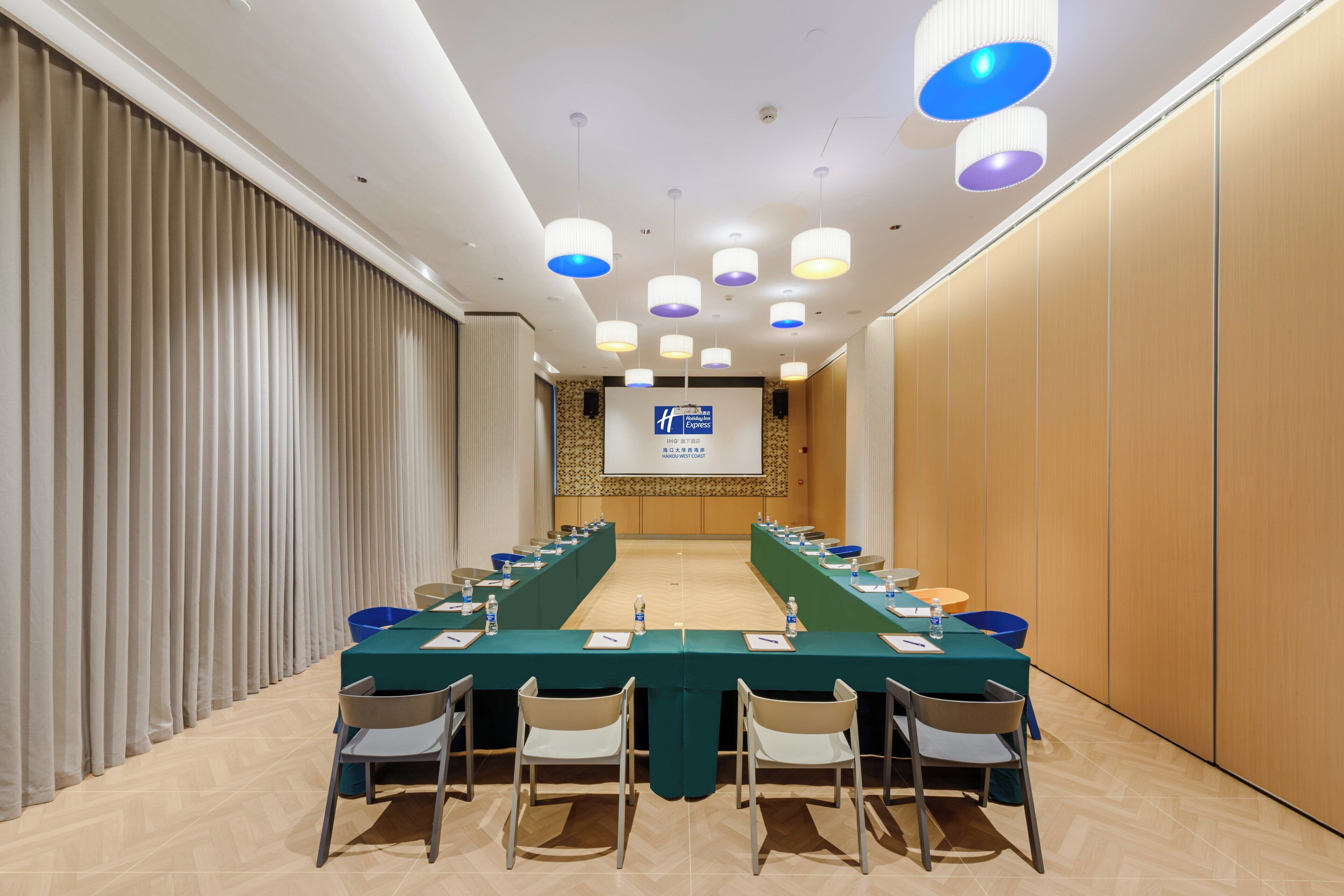A conference room with a long table, chairs, and a projection screen.