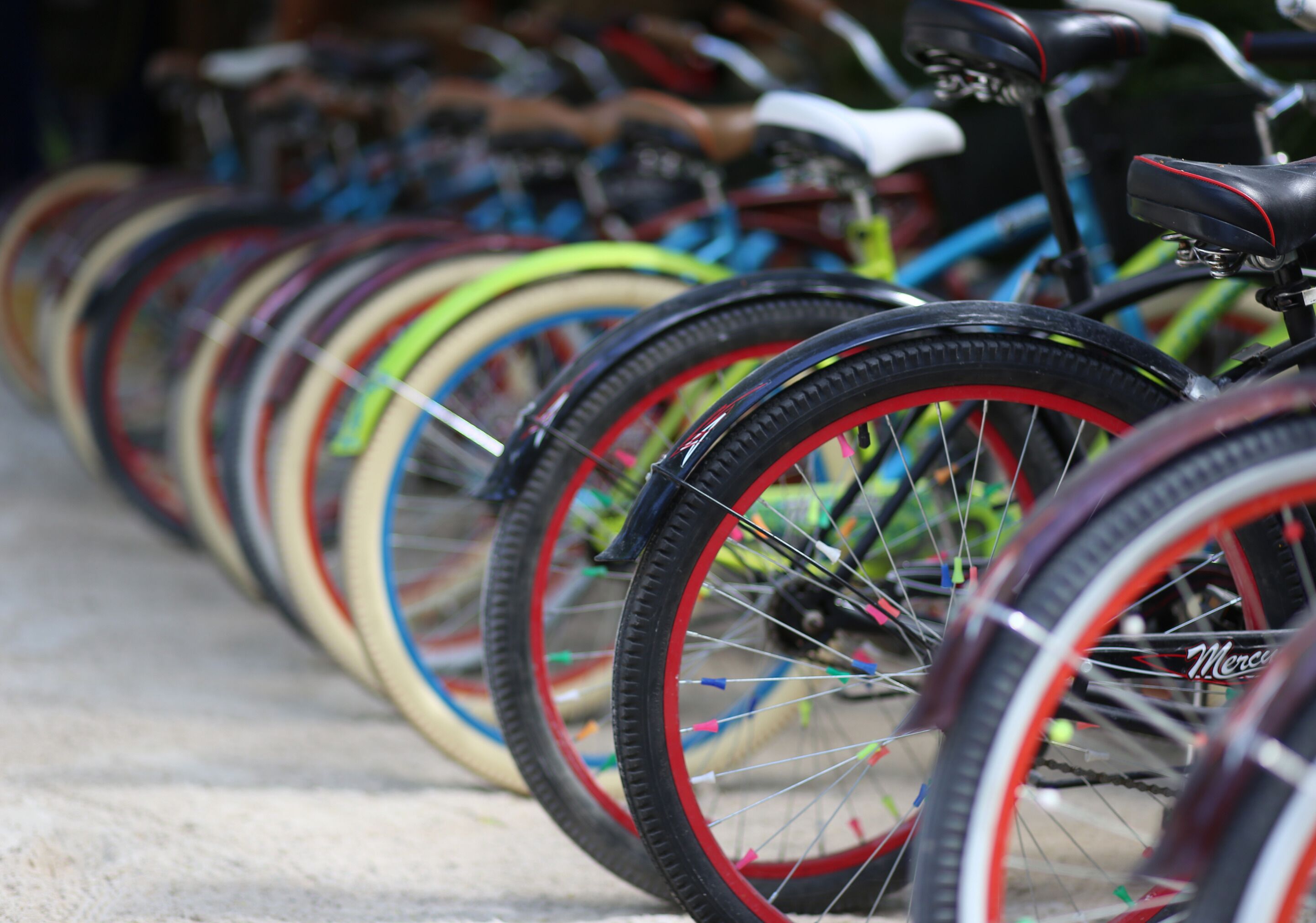A row of bicycles with various colored tires parked closely together.