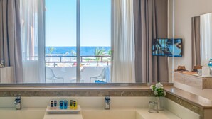 A modern bathroom with a large bathtub, a vanity with a mirror, and a television mounted on the wall. - Three Corners Equinox Beach Resort (Marsa Alam)
