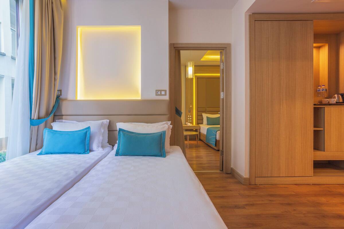 Une chambre d’hôtel avec un grand lit, une armoire en bois et une salle de bain visible à travers une porte ouverte.