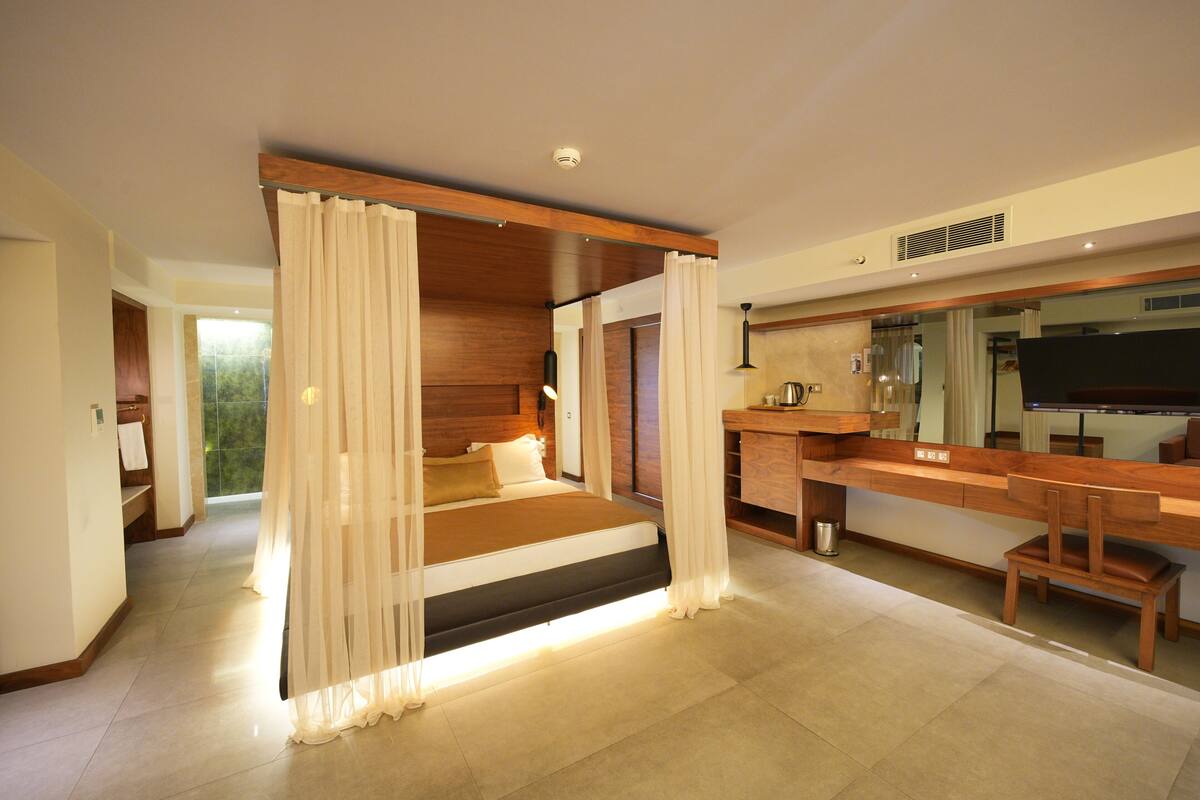 Une chambre à coucher moderne avec un grand lit, un bureau en bois et un téléviseur.