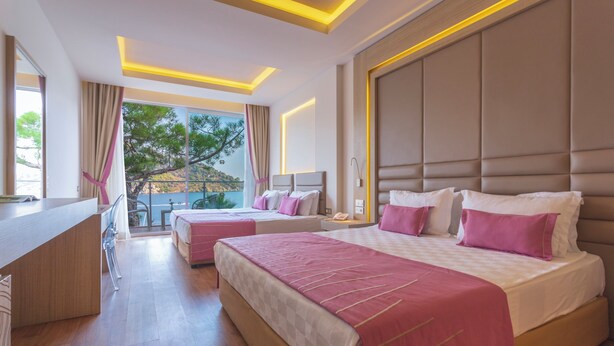 A modern hotel room with two beds, a desk, and a balcony with a view. - Orka Lotus Beach (Marmaris)