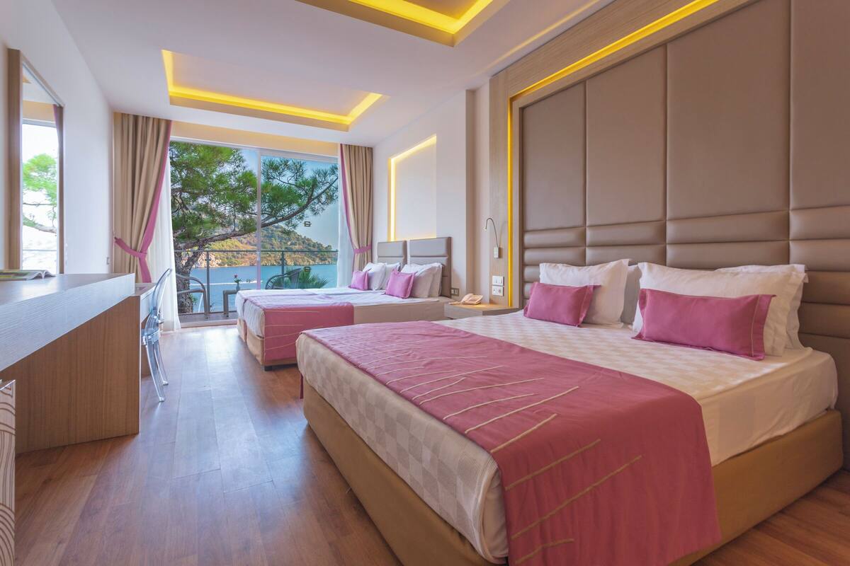 Une chambre d’hôtel moderne avec deux lits, un bureau et un balcon offrant une vue agréable.