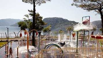 Children can play in the water play area surrounded by trees and a natural landscape.