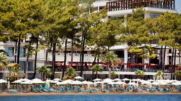 Um hotel à beira-mar com vários andares, áreas de estar ao ar livre e uma piscina.