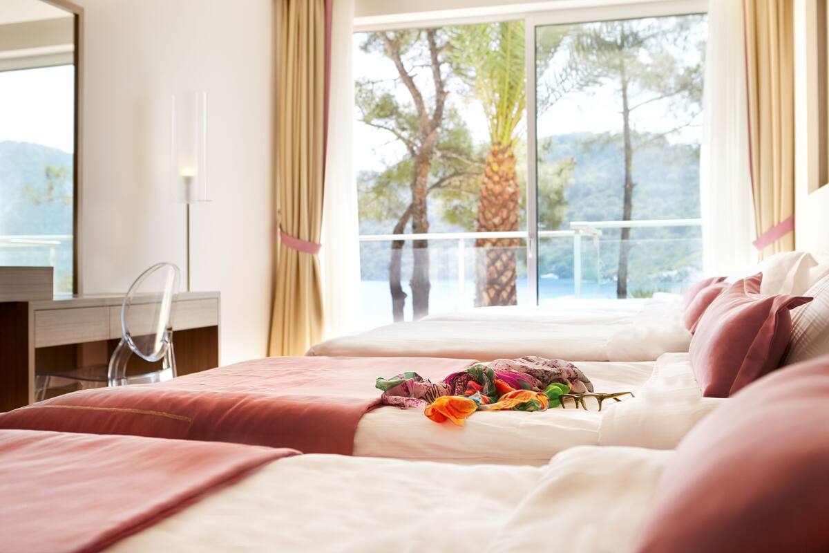 Une chambre d’hôtel avec un grand lit, un bureau et une vue sur les arbres et les montagnes par la fenêtre.