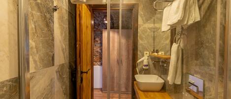A bathroom with a glass shower enclosure, a wooden vanity with a sink, and a towel rack.