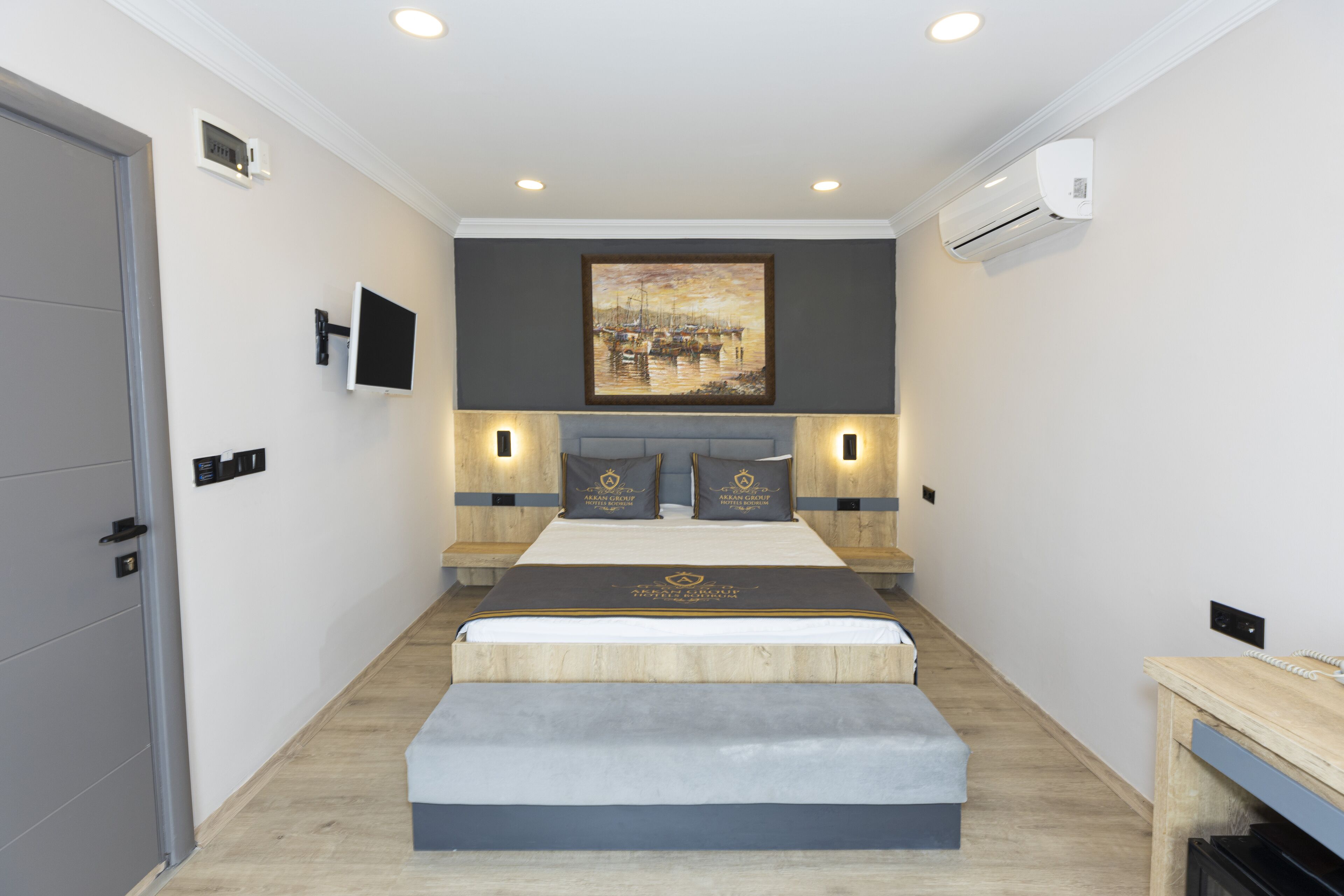 Een moderne slaapkamer met een groot bed, nachtkastjes, een schilderij en een airconditioning.