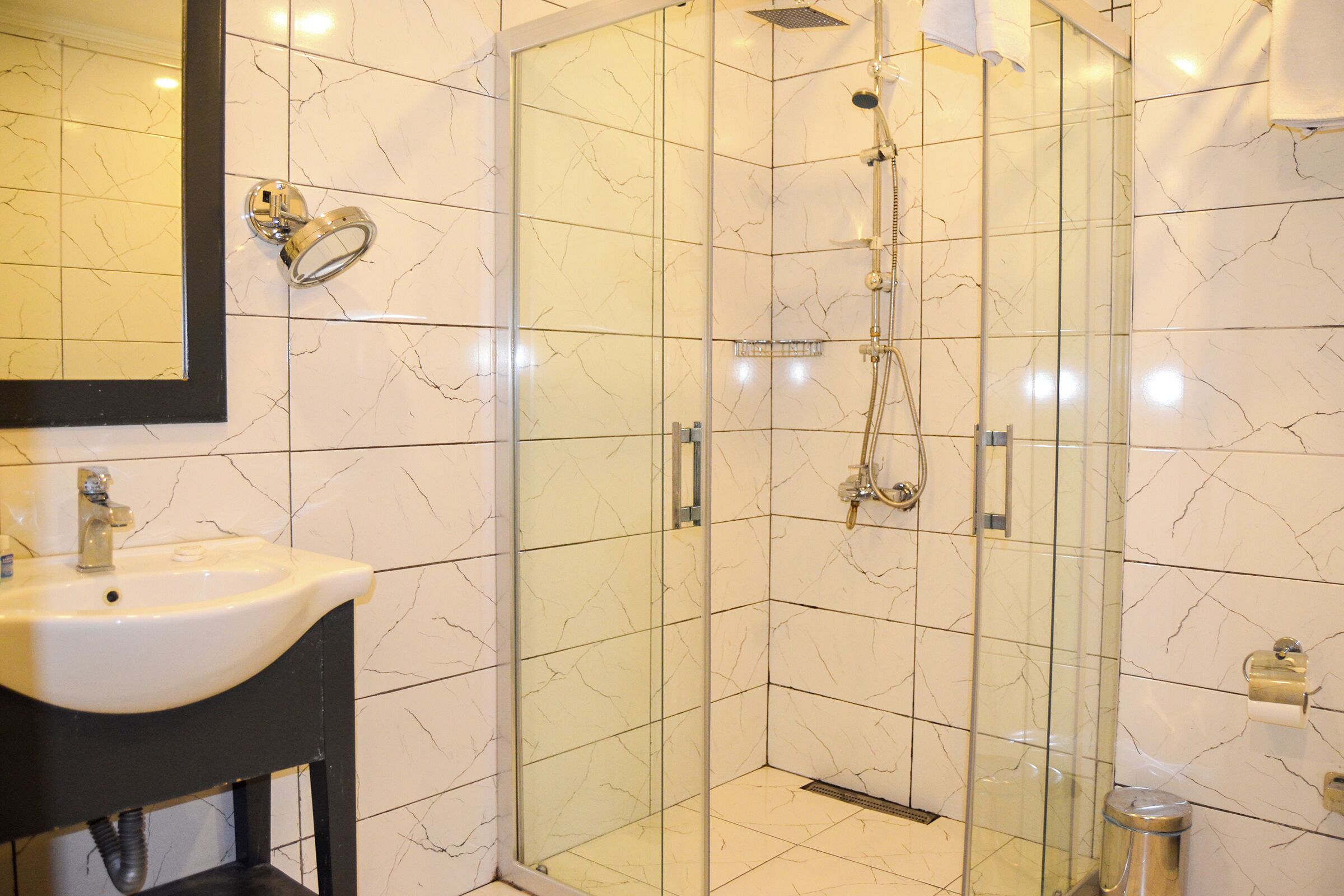 A bathroom with a glass-enclosed shower, a sink, and a mirror.