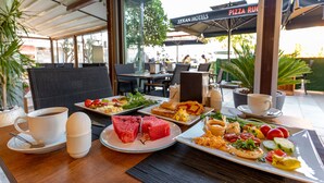 A dining table with various dishes, a cup of coffee, and a pizza umbrella. - Akkan Hotel (Bodrum)