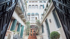 Un callejón estrecho con una puerta central que da a un edificio con múltiples ventanas y balcones.