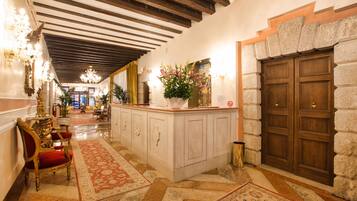 Un corridoio con soffitto in legno, parete in pietra e porta in legno.