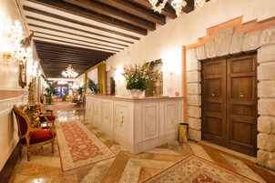 Un corridoio con soffitto in legno, parete in pietra e porta in legno.