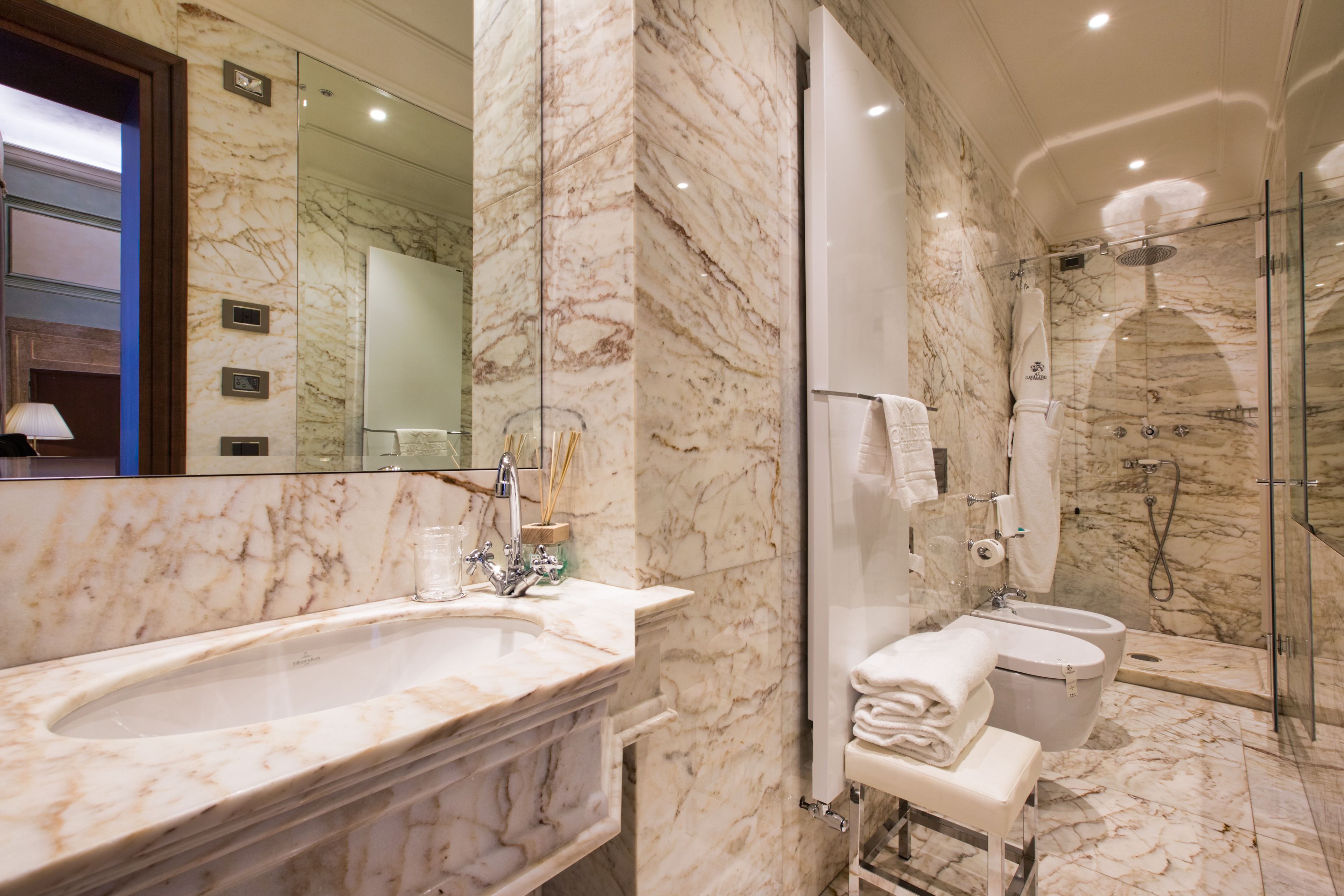 A modern bathroom with a marble sink, a glass-enclosed shower, and a toilet.
