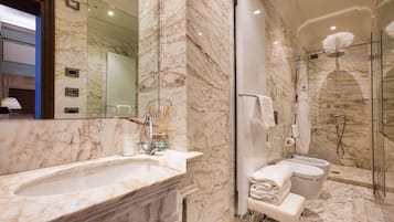 A modern bathroom with a marble sink, a glass-enclosed shower, and a toilet.