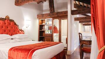 Un dormitorio con una cama grande, vigas de madera en el techo, un armario y un baño visible a través de una puerta abierta.