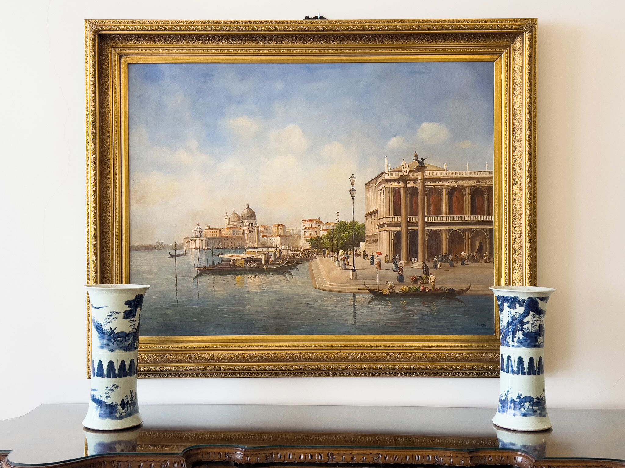 A framed painting of a canal scene with gondolas, buildings, and people.