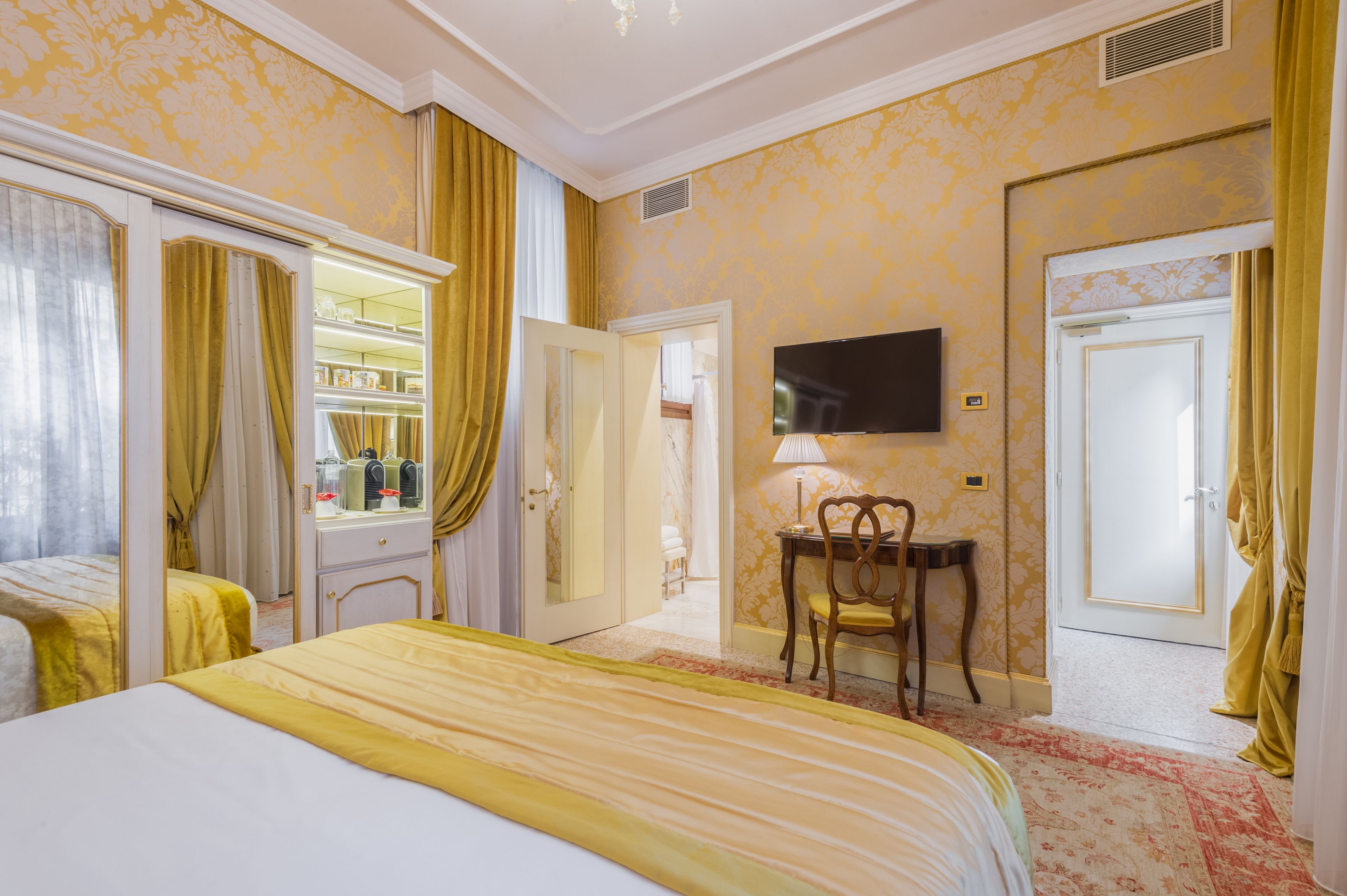 A hotel room with two beds, a television, a desk with a chair, and a wardrobe.