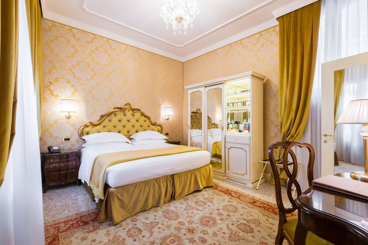Una habitación de hotel con cama, armario, escritorio y silla.