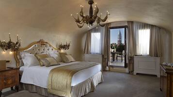 Quarto luxuoso com uma cama grande, um candelabro ornamentado e vista para uma torre pela janela.