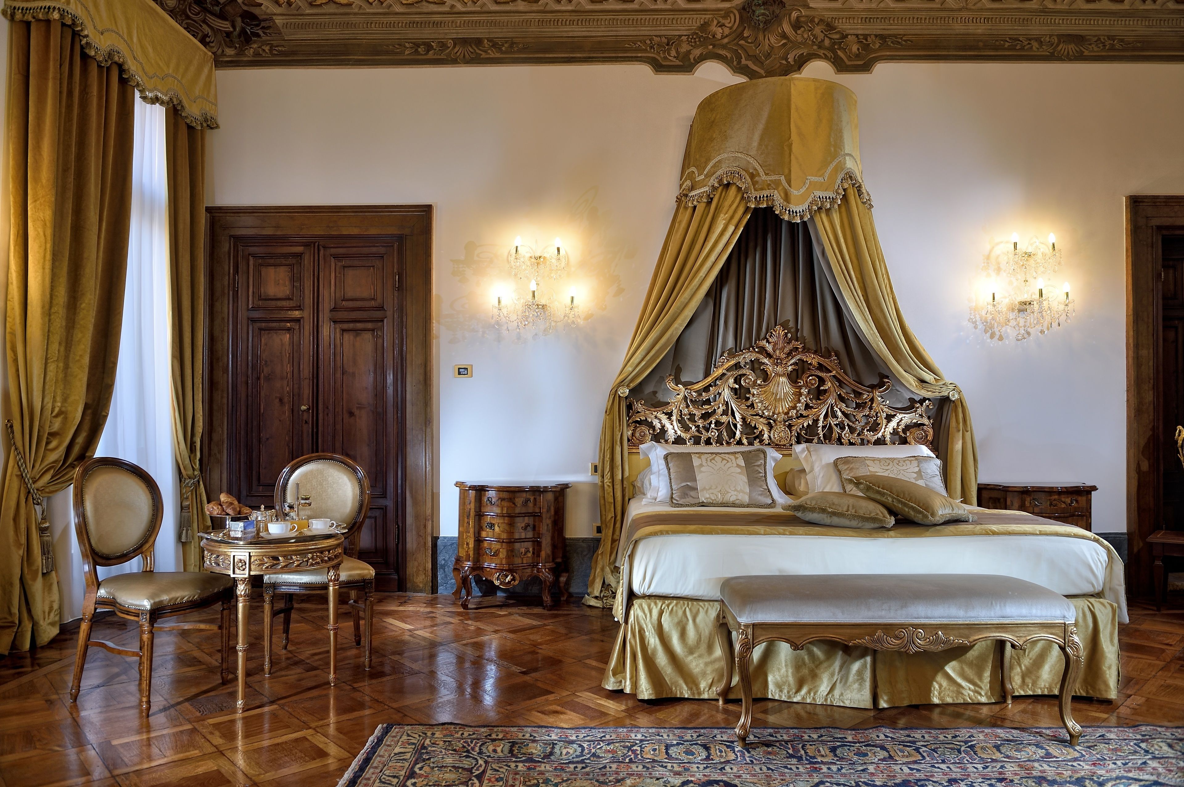 A luxurious bedroom with a large canopy bed, ornate headboard, and a classic wooden floor.