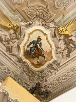 Techo detallado con un panel central ornamentado que muestra una figura a caballo, rodeado de elementos arquitectónicos y esculturas clásicas.