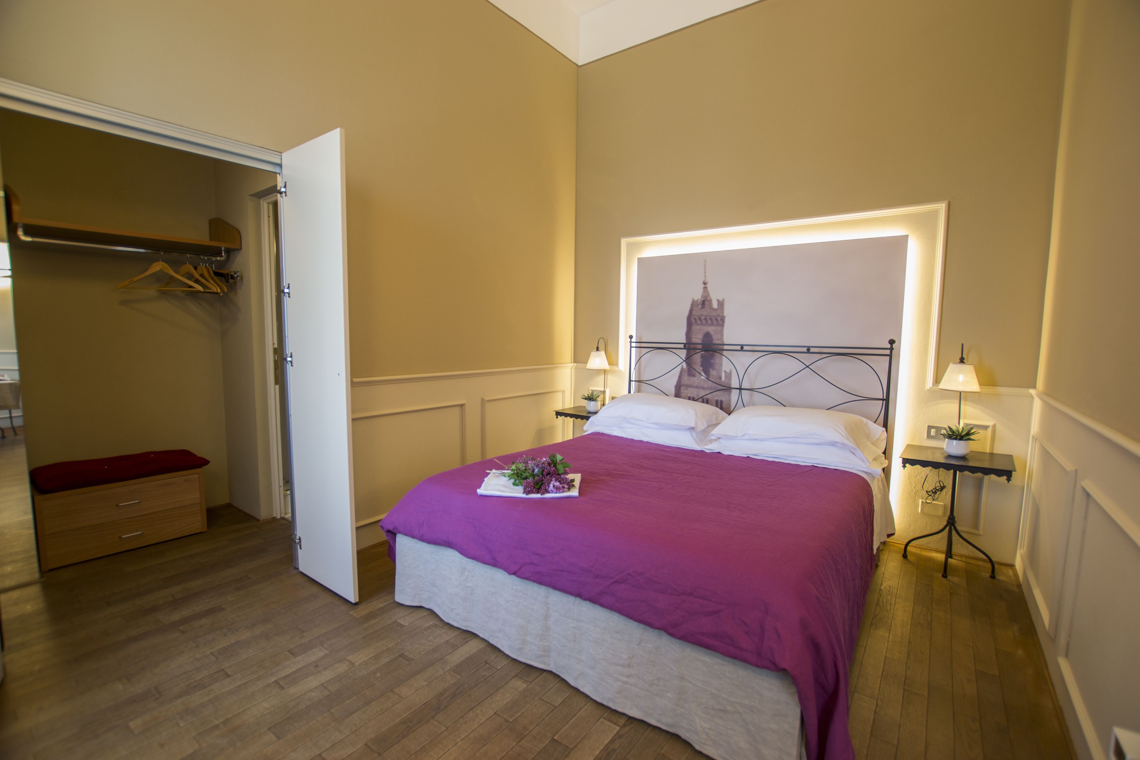 A bedroom with a bed, a nightstand, a bedside table, a wardrobe, and a door.