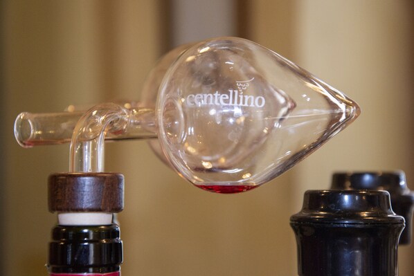 A clear glass decanter with the brand name "cantellino" on it, being filled with a red liquid from a tap.