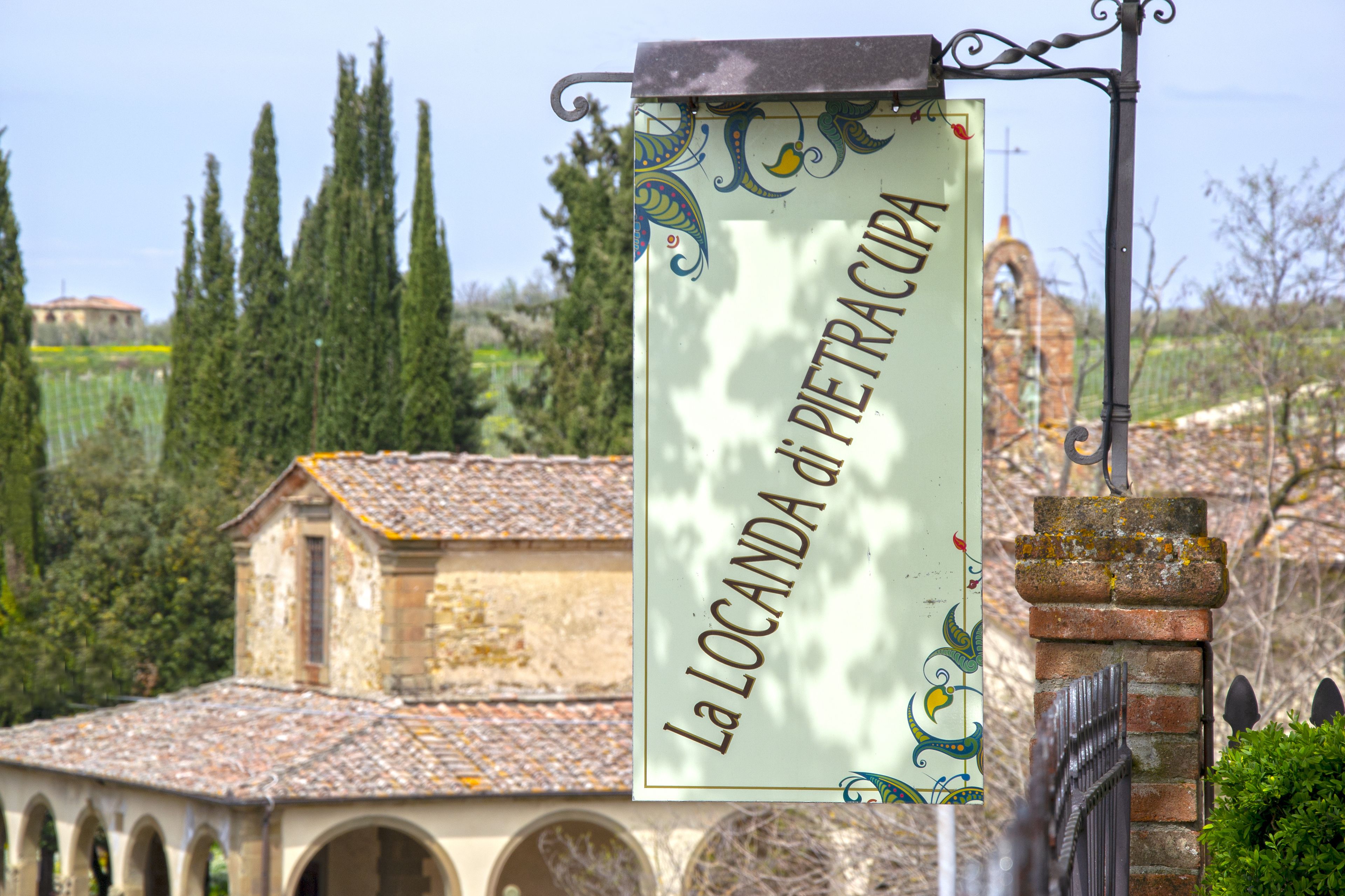 A sign with the text "La Locanda di Pietracupa" in a rustic setting with a building and trees in the background.