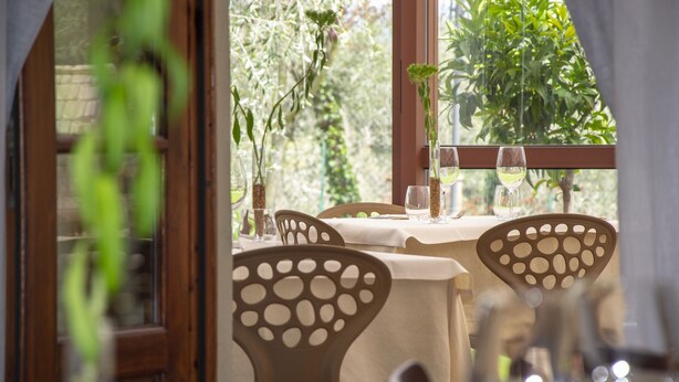 A dining area with a table set for two, featuring a view of greenery through a window. - La Locanda di Pietracupa (Barberino Tavarnelle)