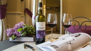 A table with a bottle of Chianti wine, two wine glasses, a book, a magazine, and a bouquet of lilacs. - La Locanda di Pietracupa (Barberino Tavarnelle)