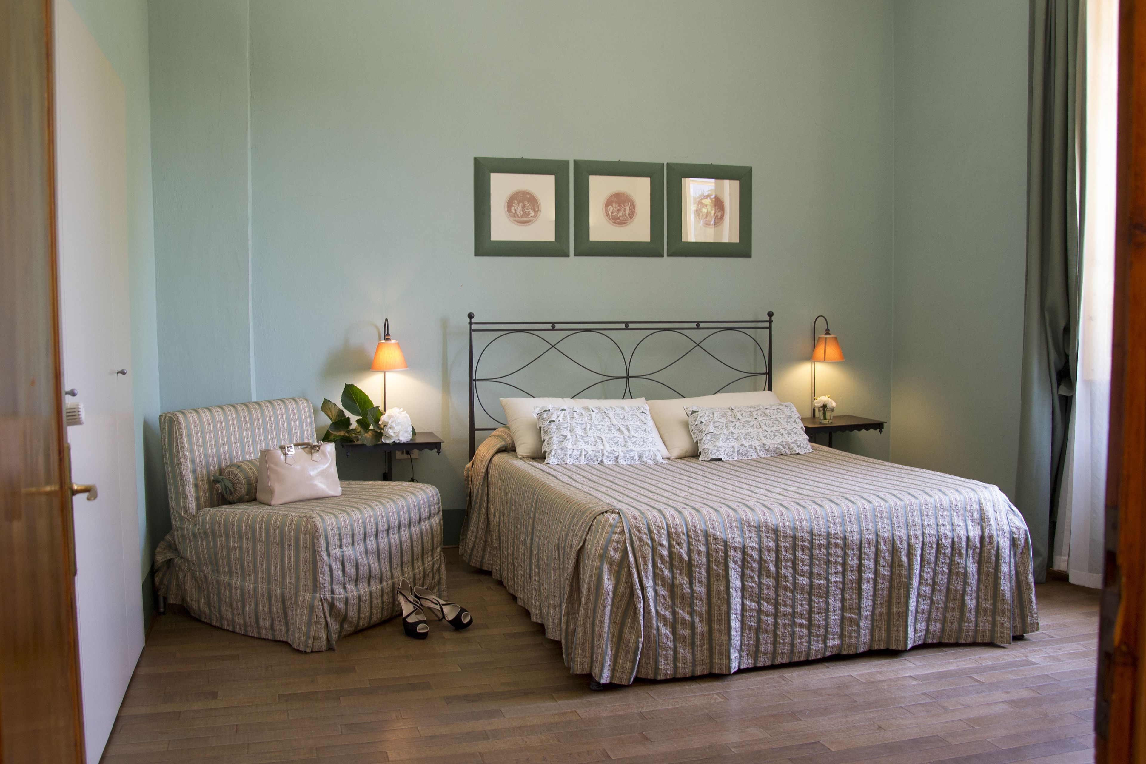 A bedroom with two beds, a chair, a nightstand, and a lamp.
