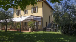 A two-story house with a patio area, potted plants, and outdoor furniture. - La Locanda di Pietracupa (Barberino Tavarnelle)