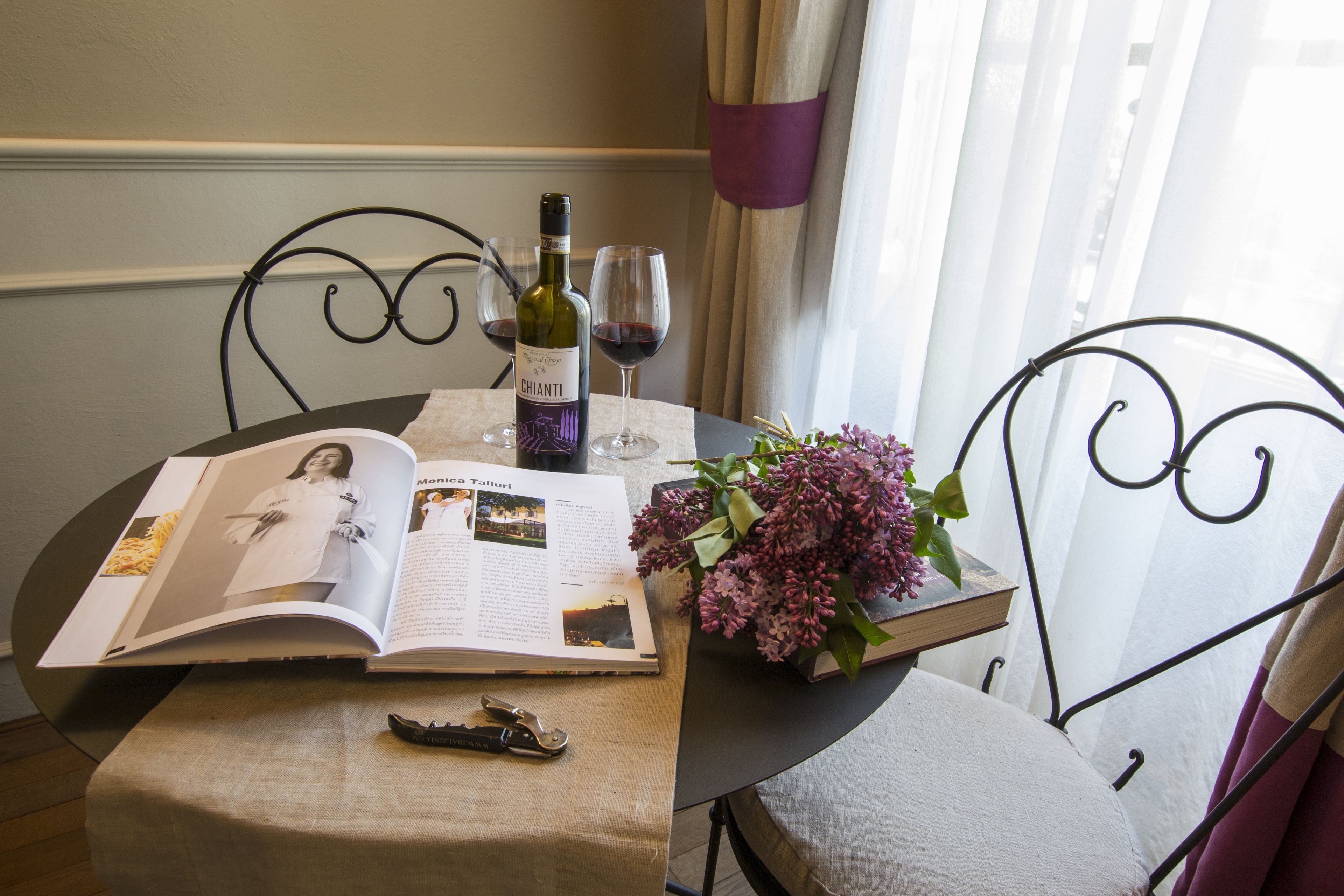 A table with a book, a wine bottle, glasses, and a bouquet of flowers.