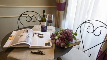 A table with a book, a wine bottle, glasses, and a bouquet of flowers.