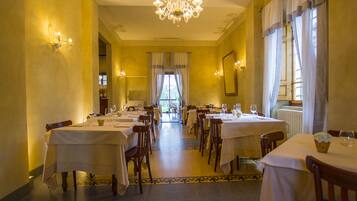 Enjoy dining in a spacious, well-organized room with elegant tables set beneath a stunning chandelier.
