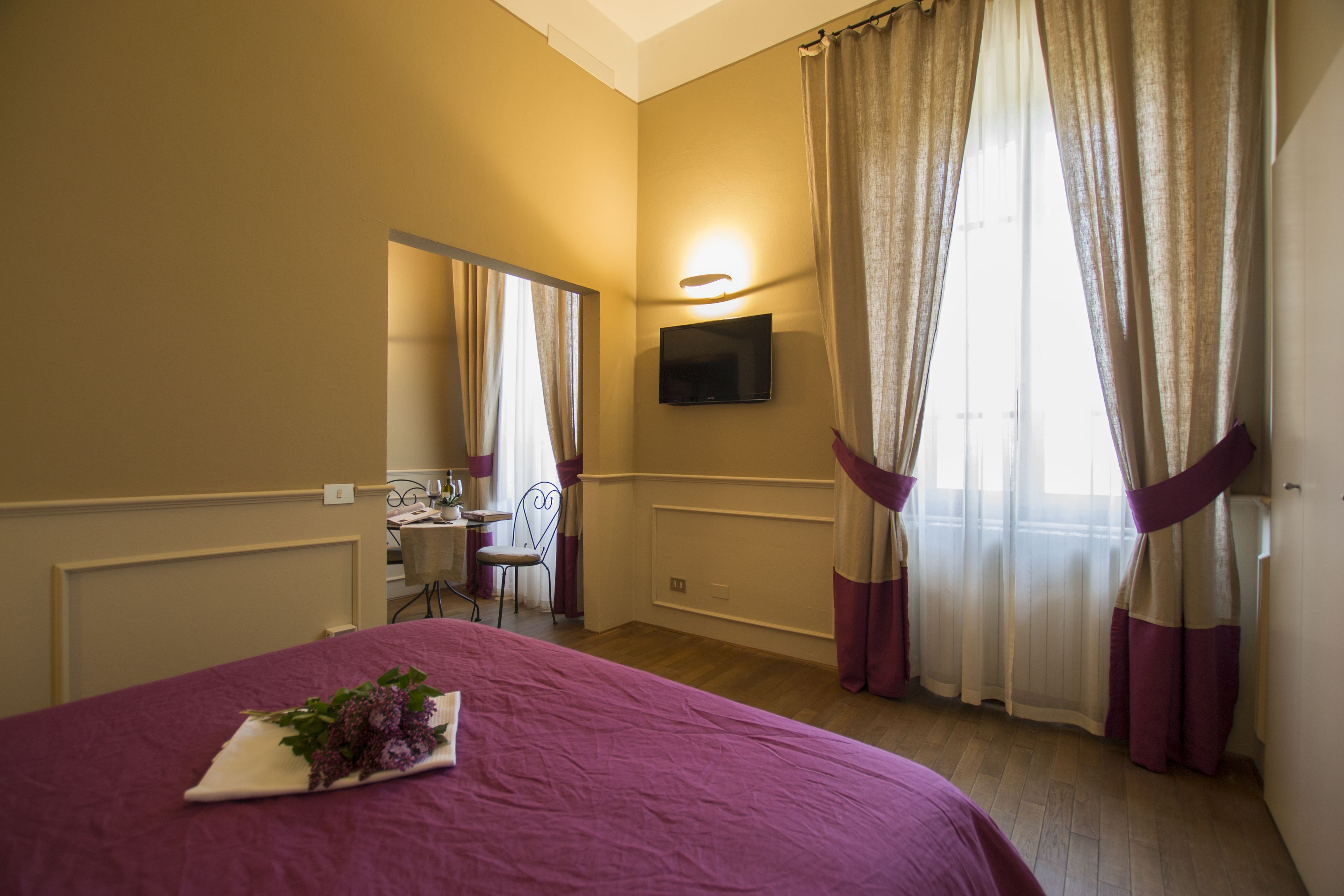 A bedroom with a bed, a desk, a chair, a TV, and curtains.