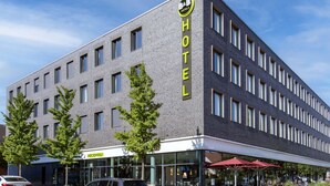 Un moderno edificio de hotel con un llamativo letrero que dice 'HOTEL', una zona de recepción y asientos al aire libre.