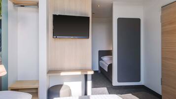 Ein modernes Hotelzimmer mit Bett, Schreibtisch, Flachbildfernseher und Kleiderschrank.