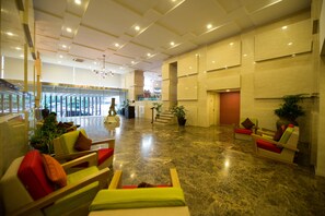 A spacious lobby with a polished marble floor, seating areas with colorful cushions, and potted plants. - Hotel Parami (Yangon)