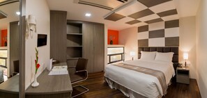 A hotel room with a bed, bedside table, chair, desk, and a large mirror. - Hotel Parami (Yangon)