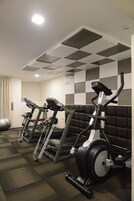Un gimnasio con tres bicicletas estáticas, una pelota de ejercicios grande y una pared a cuadros.