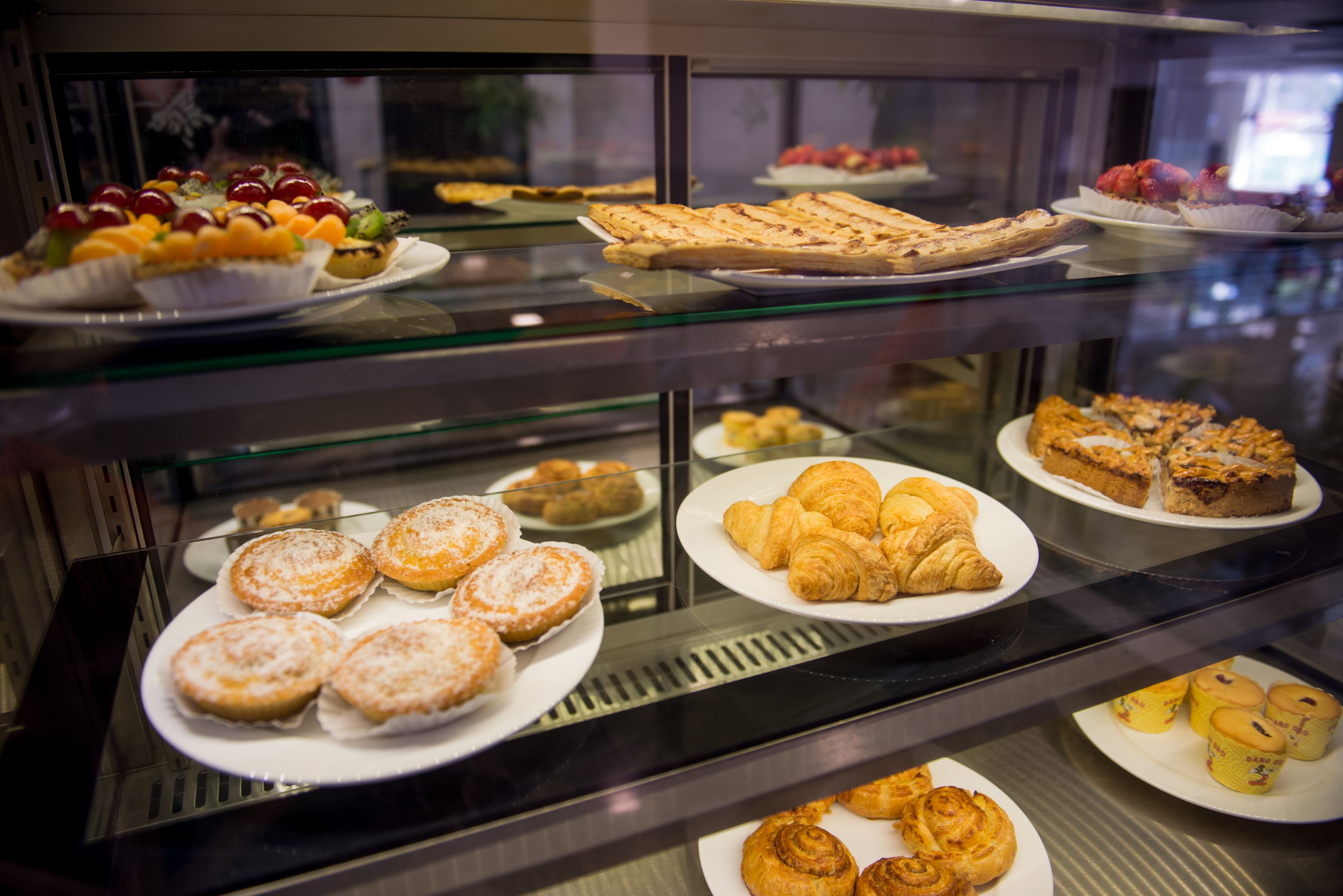 Una vitrina con diversos pasteles y postres.