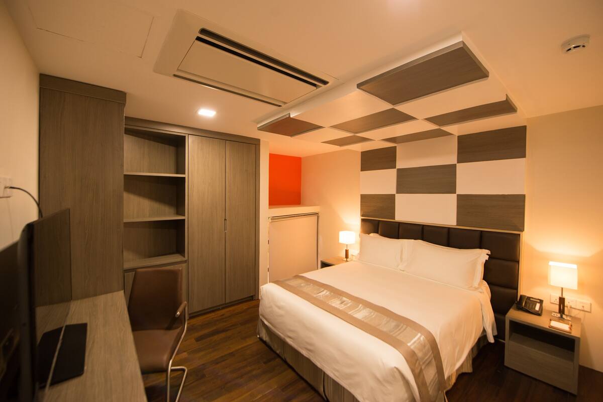Ein Hotelzimmer mit Bett, Nachttisch, Lampe und Kleiderschrank.