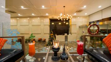 A lobby with a Christmas tree, a chandelier, and two drinks on a glass table.