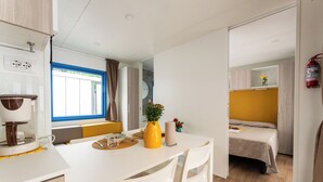 A compact room with a dining table, chairs, a bed, and a small window with curtains. - Adria Holiday Pra' delle Torri (Caorle)